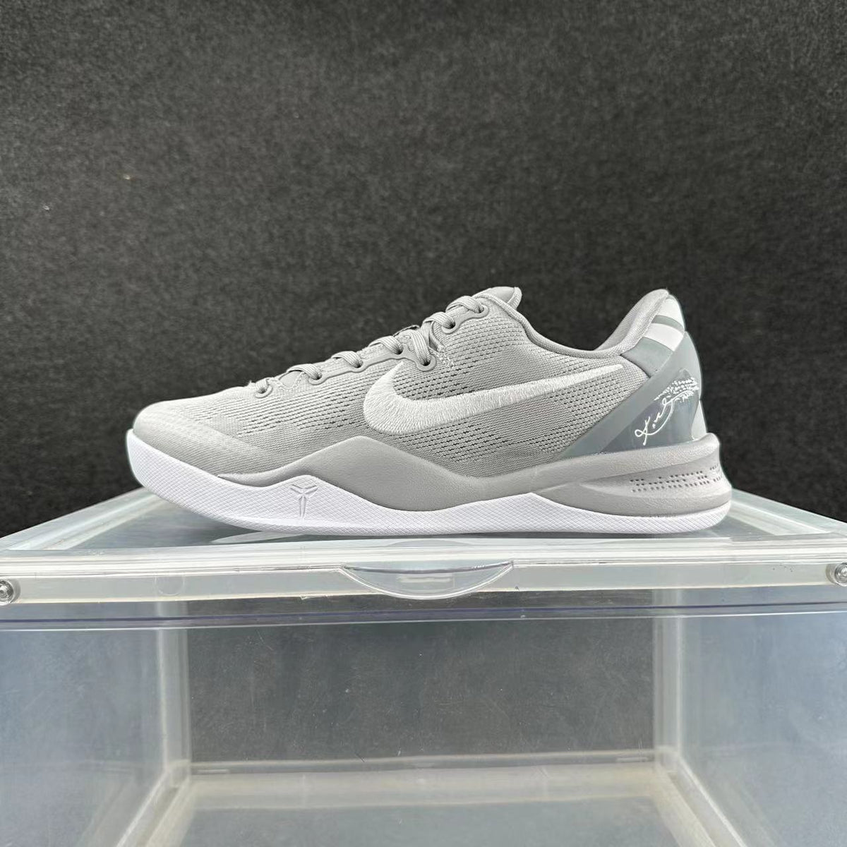 Gray and white low-top Nike shoe with a white Swoosh and signature-style heel detail