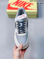 Top view of the Nike Air Force 1 sneaker showing the grey perforated toe panel, navy laces and white tongue.