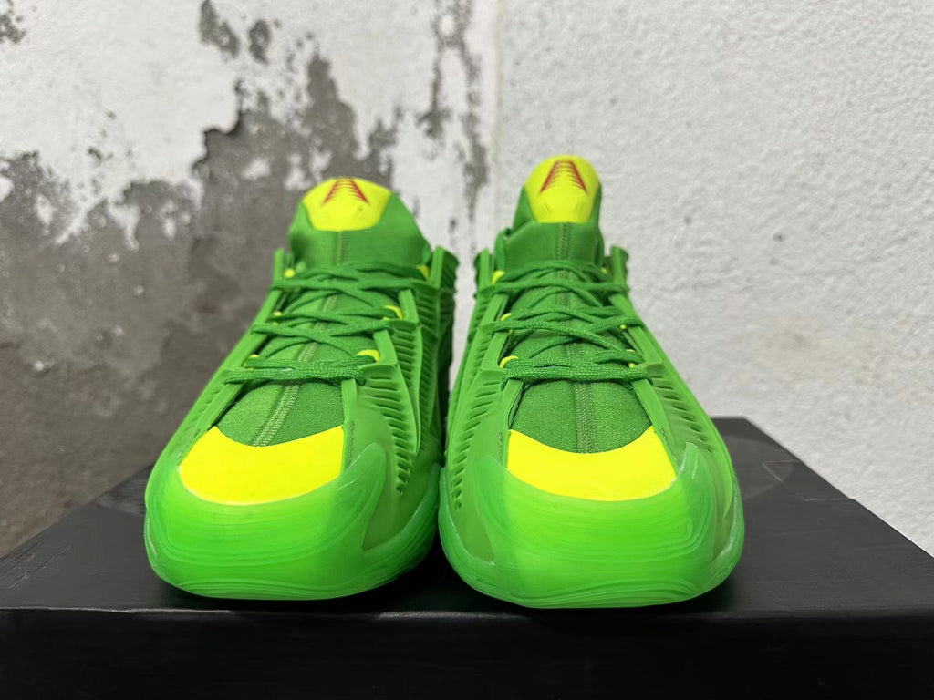 Front view of green Adidas sneakers with bright yellow toe and tongue accents