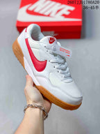 Angled side view of the white and red sneaker with its gum-colored sole and layered upper panels.