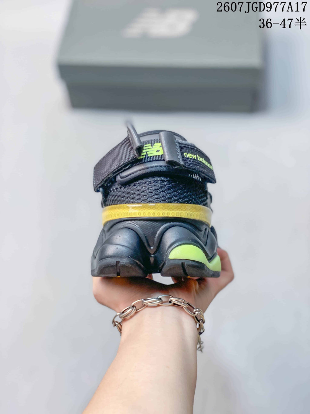 Rear view of the black New Balance 9060 sneaker showing the fold-down heel area, yellow heel accent and fluorescent yellow outsole detail.