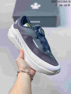 Side view of a black Descente sneaker held in hand, showing the perforated upper, dial closure and layered sole.