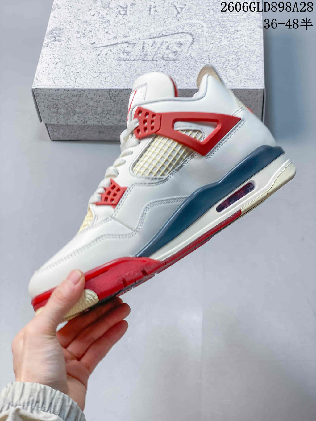 Side view of the white mid-top sneaker with red lace wings, mesh panels, grey midsole detail, and visible air unit.