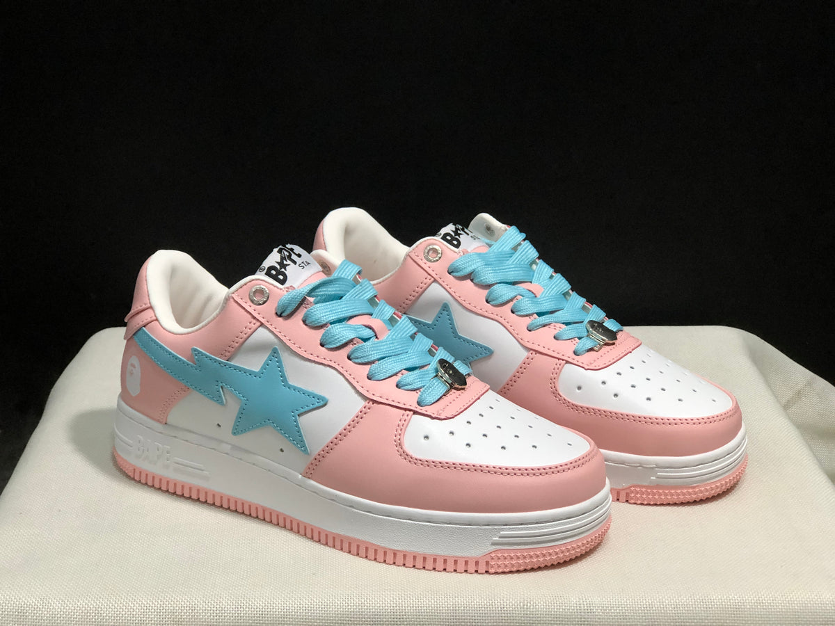 Three-quarter view of the pair highlighting the light-blue side emblems, pink overlays, and white midsoles.