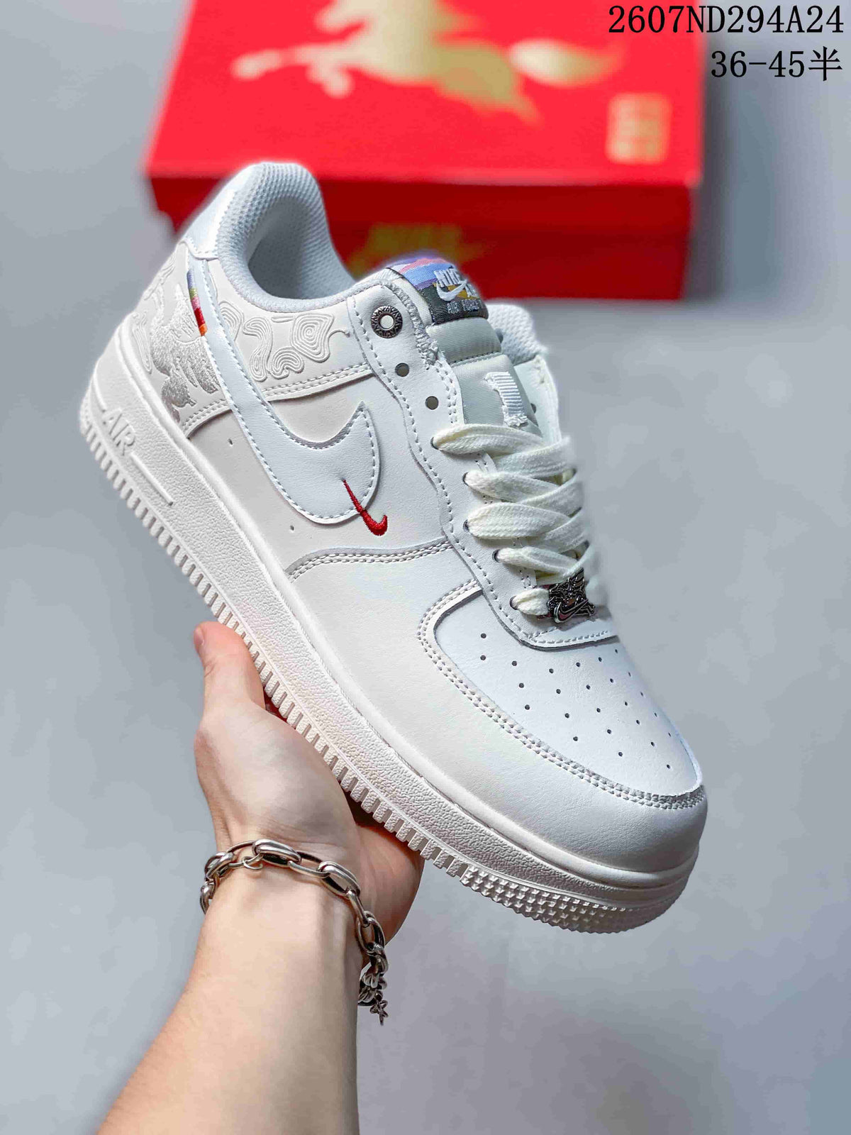Angled side view of the white Nike Air Force 1 '07 low-top sneaker showing the Swoosh, red accent detail, decorative upper panels and textured outsole.