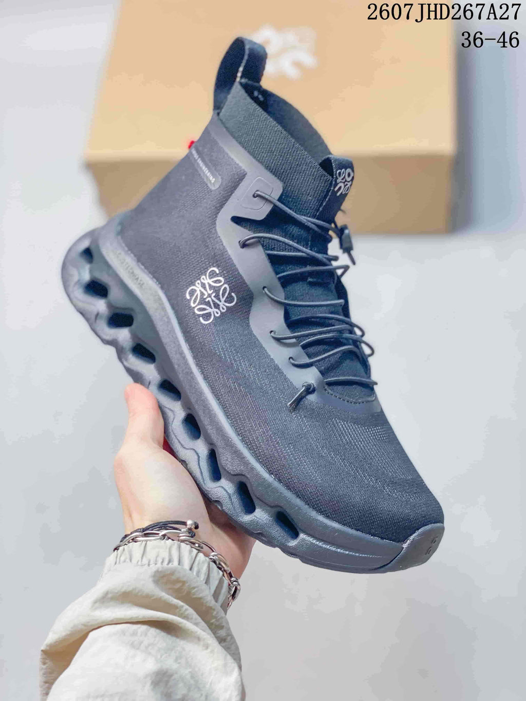 Angled side view of a dark gray LOEWE x On Cloudtilt sneaker showing white branding, high ankle collar, lace system and segmented outsole.