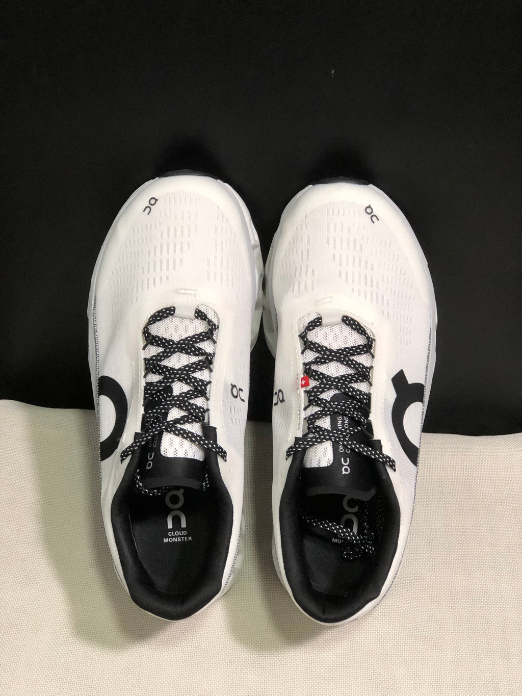 Top view of a pair of white On Cloudmonster 2 shoes with black patterned laces