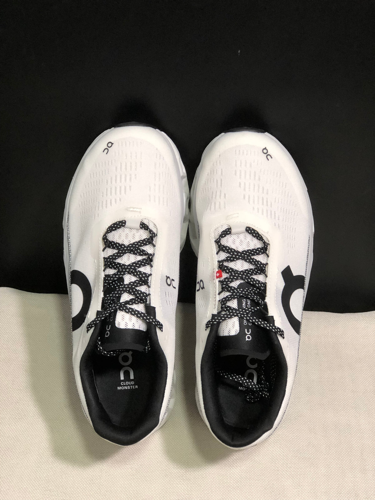 Top view of a pair of white On Cloudmonster 2 shoes with black patterned laces