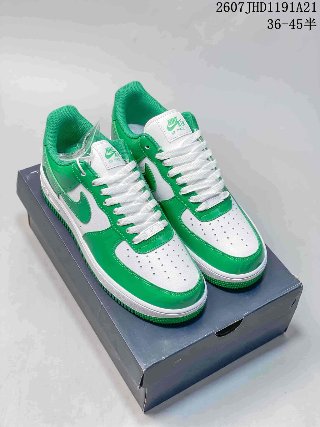 Green-and-white Nike Air Force 1 sneakers displayed on a shoe box, with white laces and a visible box label showing the size range text.