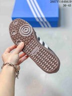 Close view of the brown gum-colored outsole showing a geometric tread pattern and adidas branding; the background includes an adidas shoe box.