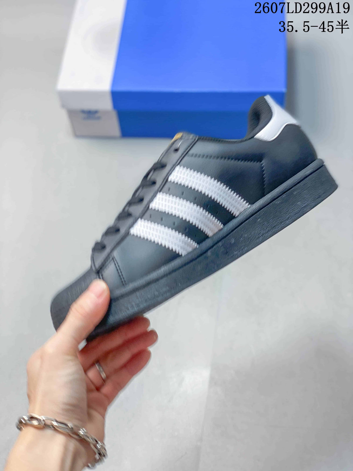 Side view of the black sneaker showing the white serrated three stripes and dark sole.