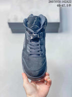 Front view of the black high-top sneaker showing the padded tongue, Jordan logo, gray laces and lace toggle.