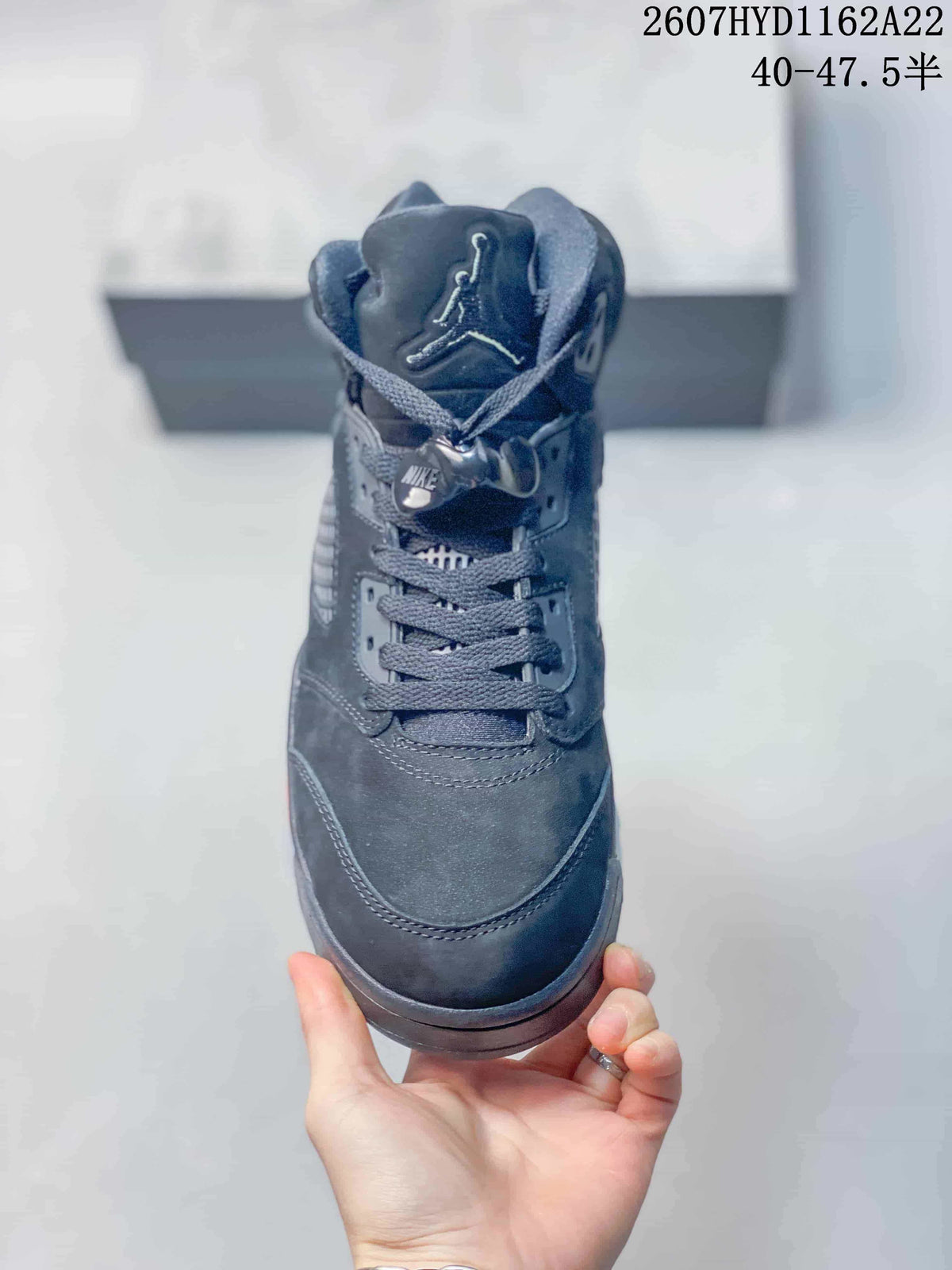 Front view of the black high-top sneaker showing the padded tongue, Jordan logo, gray laces and lace toggle.