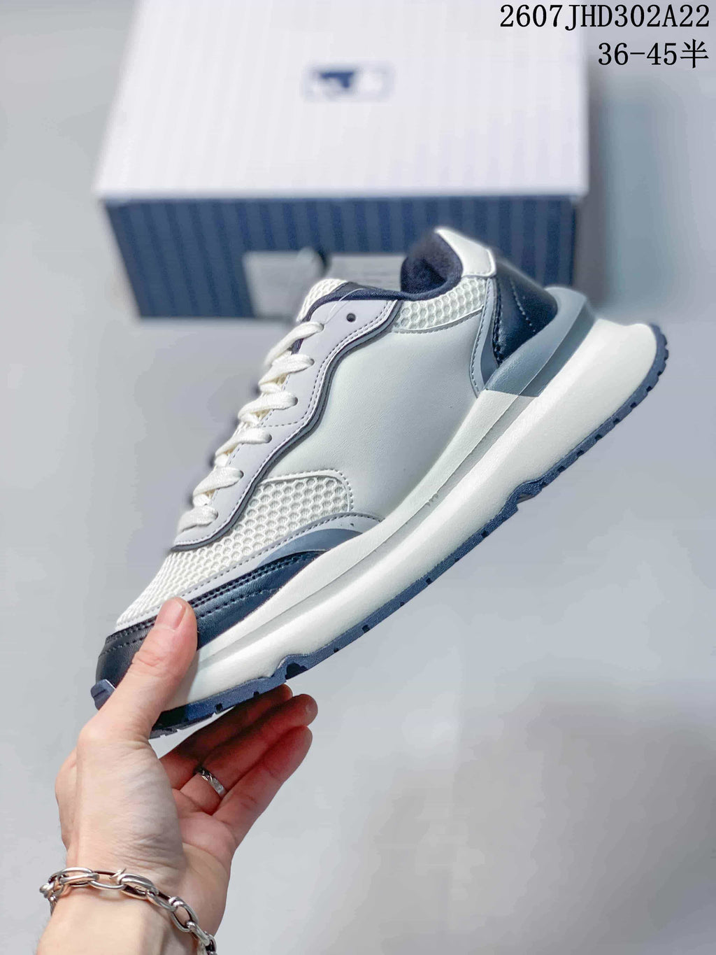 Side profile of the white and navy low-top sneaker showing the layered upper, mesh-look panels, and raised sole.