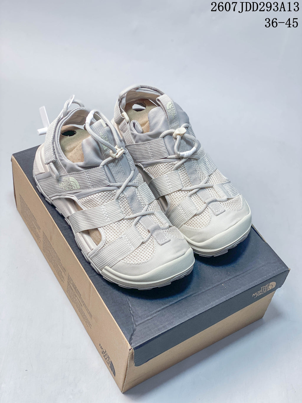 Pair of light gray The North Face outdoor sandals displayed on a shoebox, with style code 2607JDD293A13 and size range 36–45 visible above.