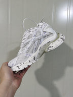 Rear-side view of the white sneaker showing the layered heel structure, mesh upper, and sculpted outsole.