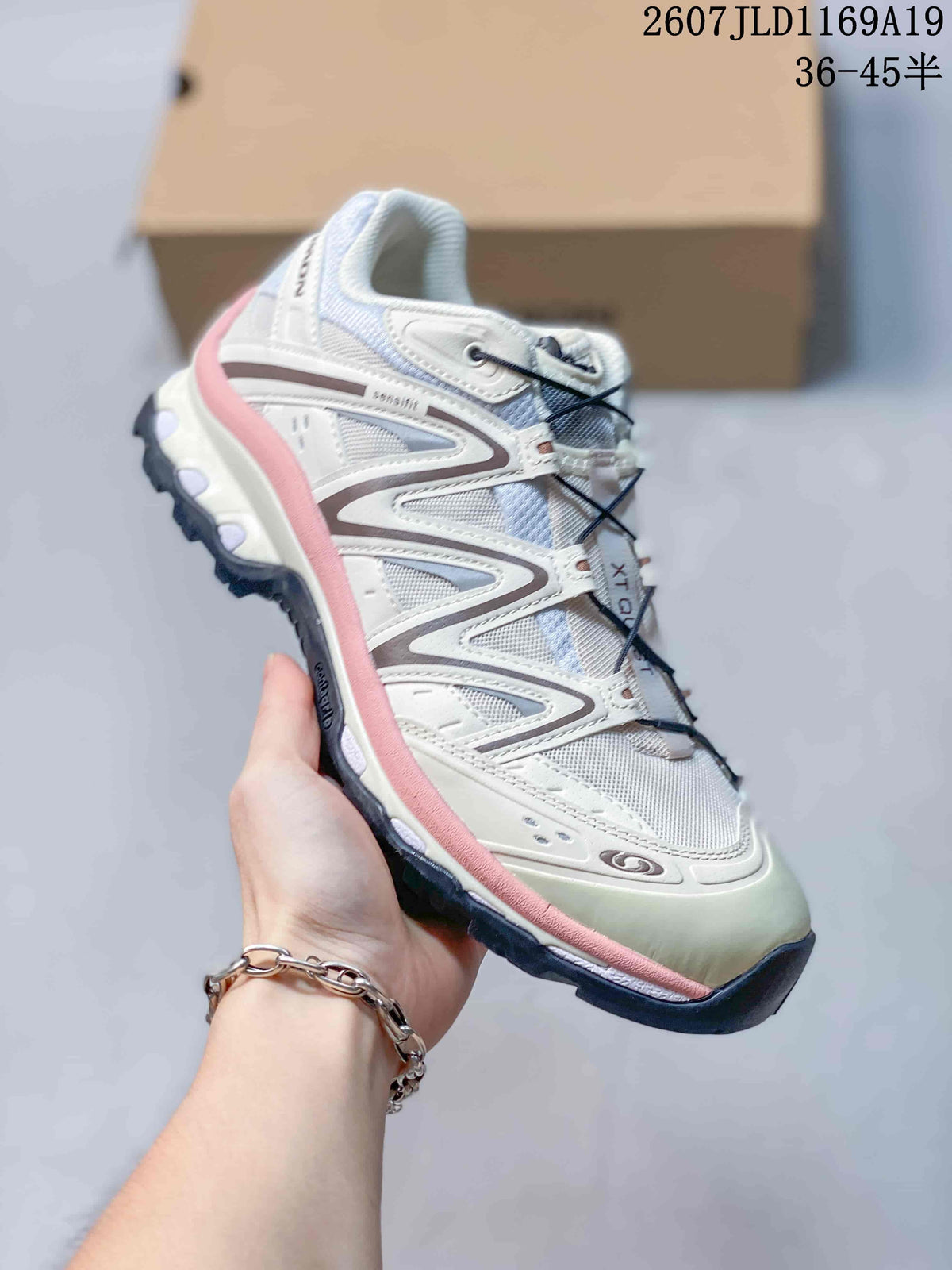 Side view of a white Salomon XT-Quest sneaker with pink trim, layered upper panels and a rugged dark outsole.