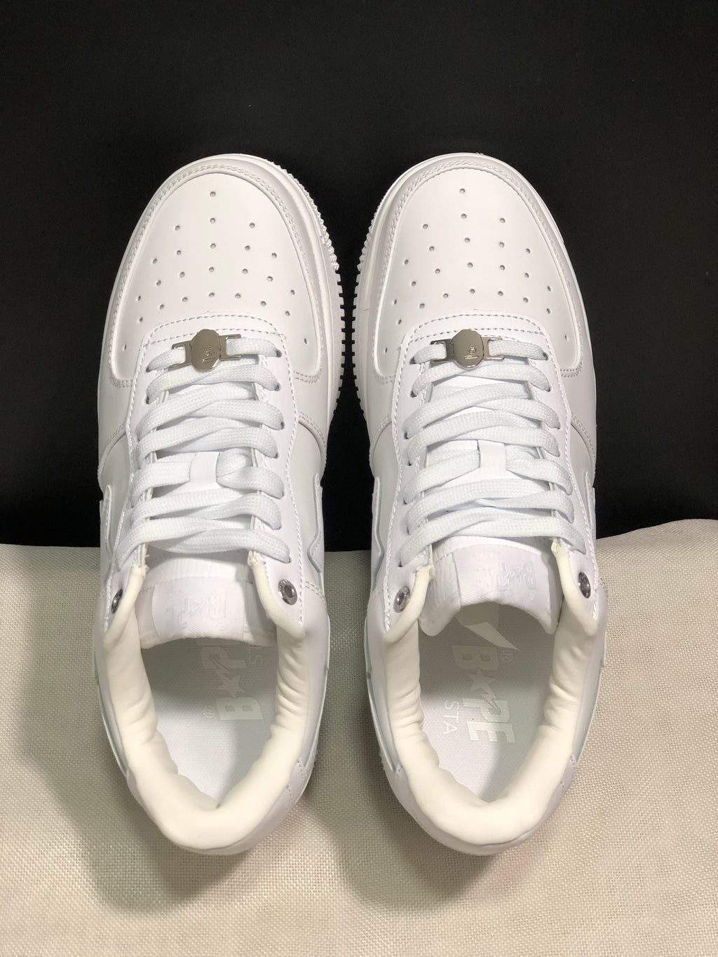 Top view of the white pair showing perforated toe boxes, white laces, and metal lace details.