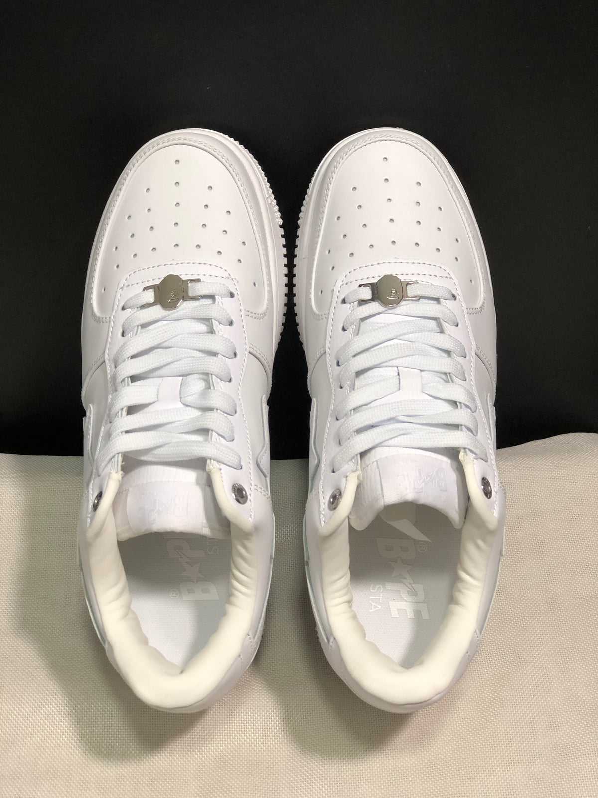Top view of the white pair showing perforated toe boxes, white laces, and metal lace details.