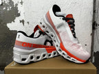Pair of white On Running sneakers with orange-red details and chunky white soles