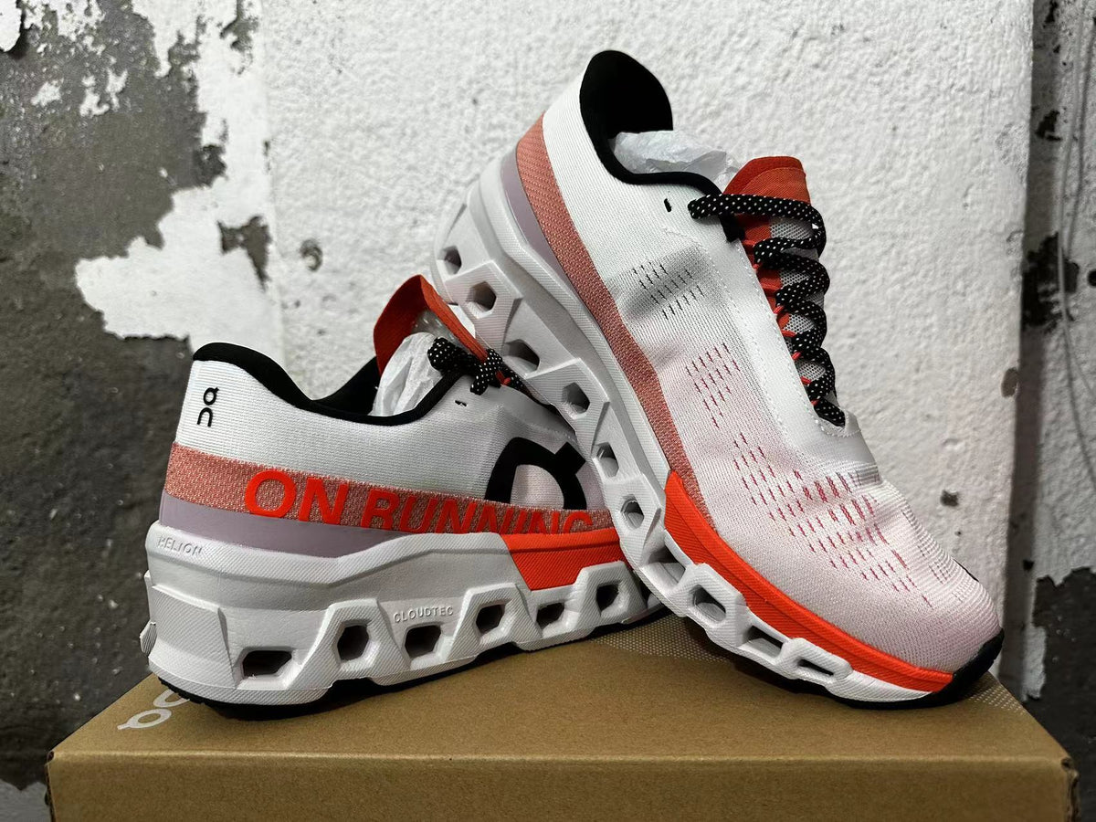 Pair of white On Running sneakers with orange-red details and chunky white soles