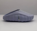 Side view of a purple Nike slide showing the sculpted sole, perforated upper, and side Swoosh detail.