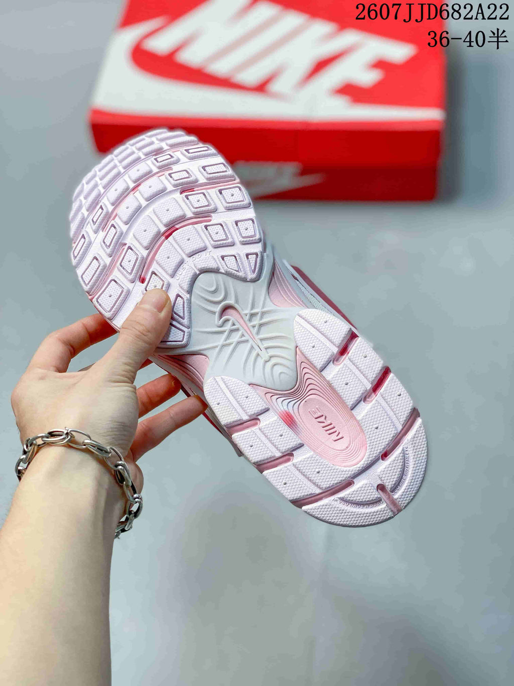 Close view of the textured white and pink outsole with the sneaker box in the background.