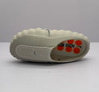 Top and side view of one beige Nike sandal with perforations, a dark Swoosh, and printed insole graphics.