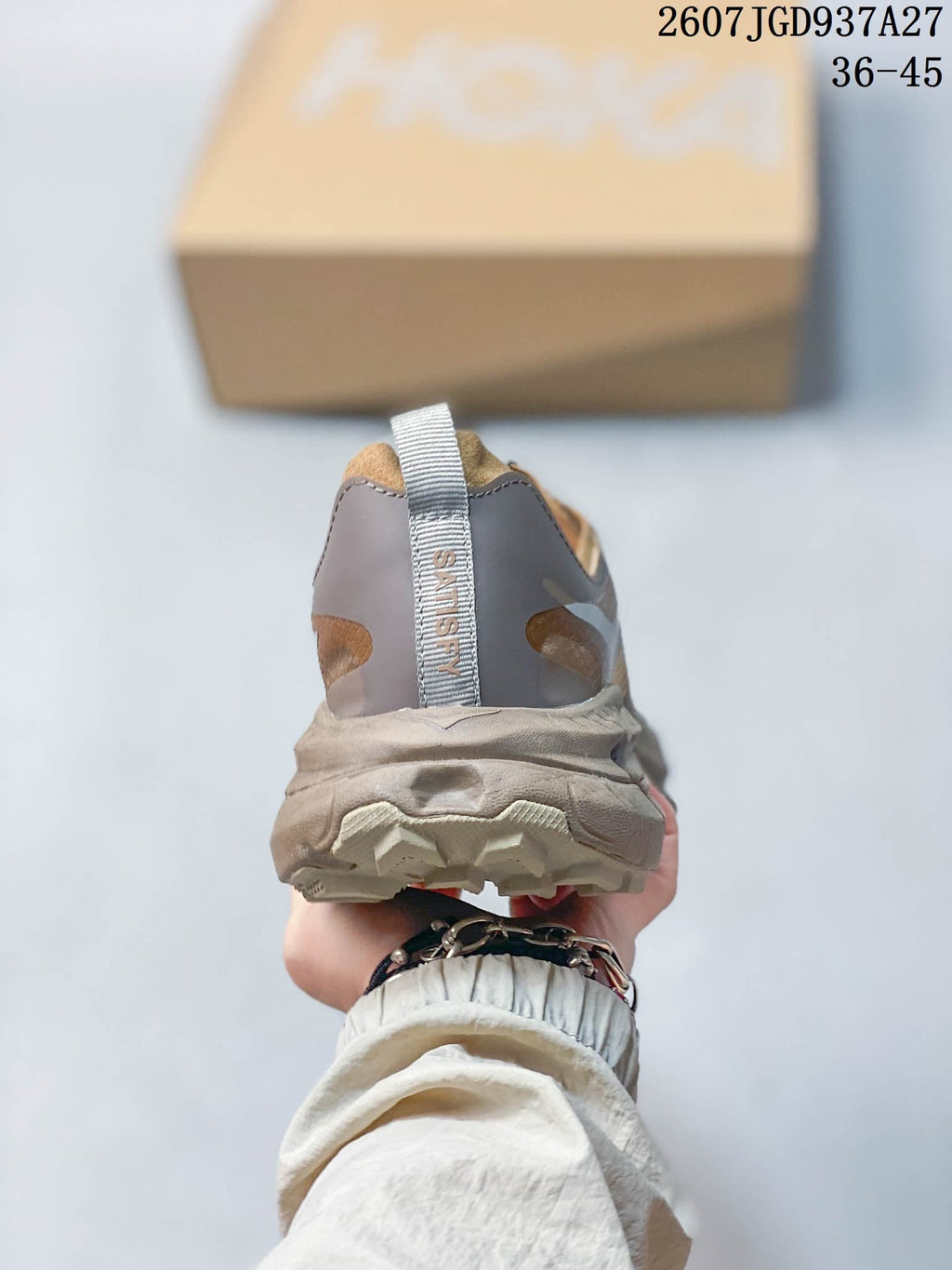 Rear view of a brown and taupe sneaker showing the padded heel, pull tab, and SATISFY branding.