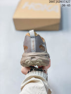 Rear view of a brown and taupe sneaker showing the padded heel, pull tab, and SATISFY branding.