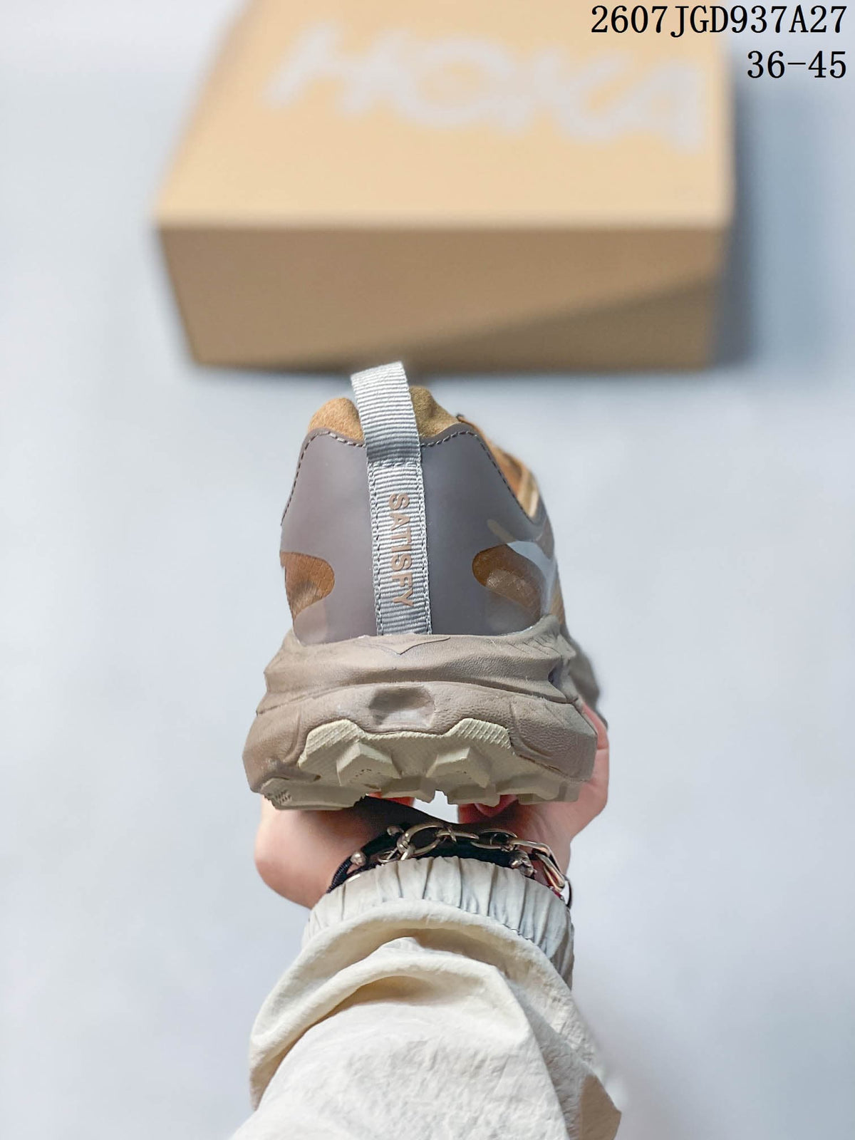 Rear view of a brown and taupe sneaker showing the padded heel, pull tab, and SATISFY branding.