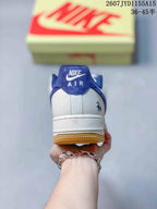 Rear view of a Nike Air Force 1 sneaker showing the blue collar, white heel panel and gum outsole.