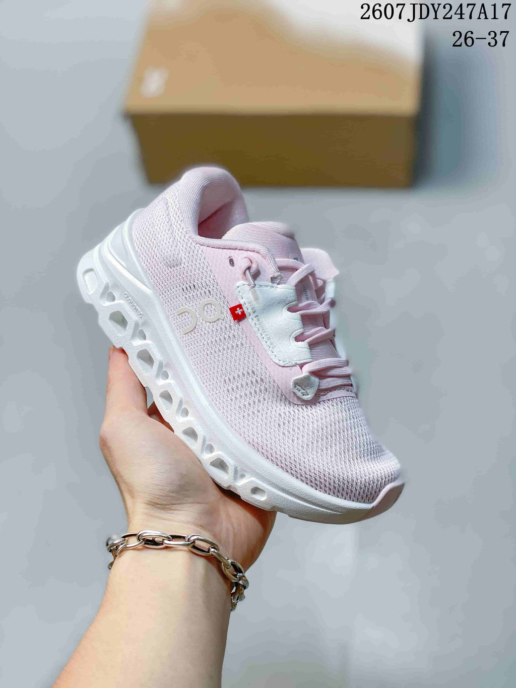 Angled side view highlighting the On side logo, pale pink upper, and segmented white outsole.