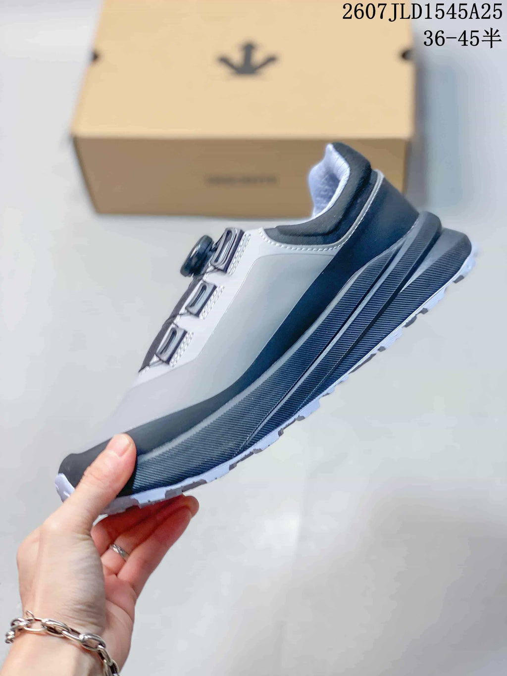 Side profile of the low-top sneaker showing the gray upper, black overlays, layered midsole, and outsole edge.