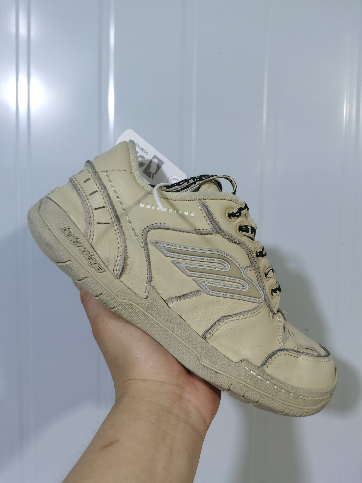 Close angled view of the khaki Balenciaga sneaker showing the heel, side branding, stitched panel outlines, and rubber outsole.