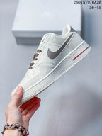 Side view of the white low-top sneaker with a brown Swoosh and red outsole detail.