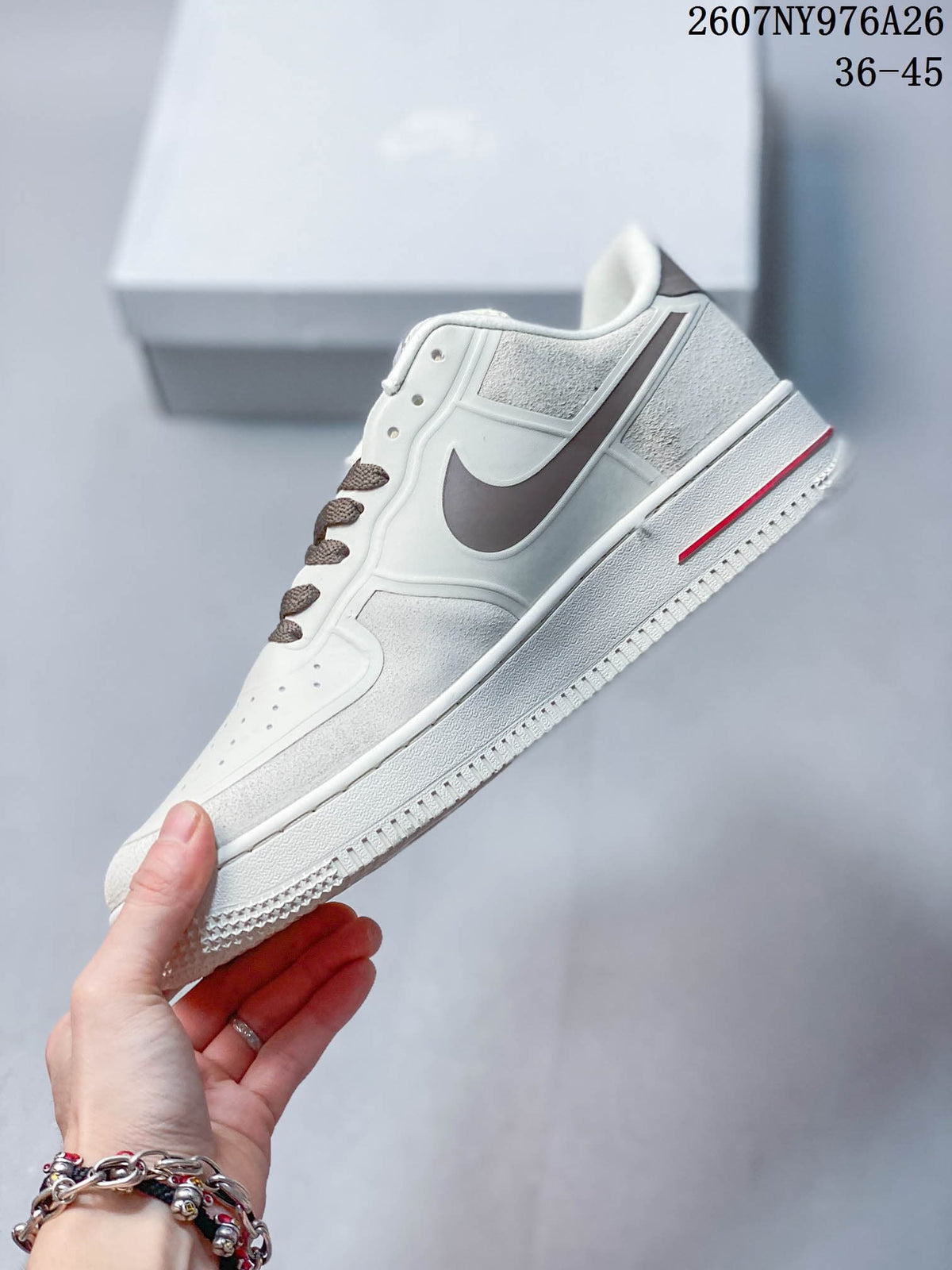 Side view of the white low-top sneaker with a brown Swoosh and red outsole detail.