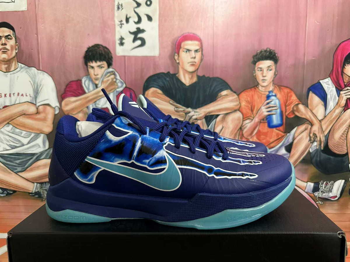 Side profile of a navy and blue Kobe basketball shoe with light blue accents and an aqua-colored outsole