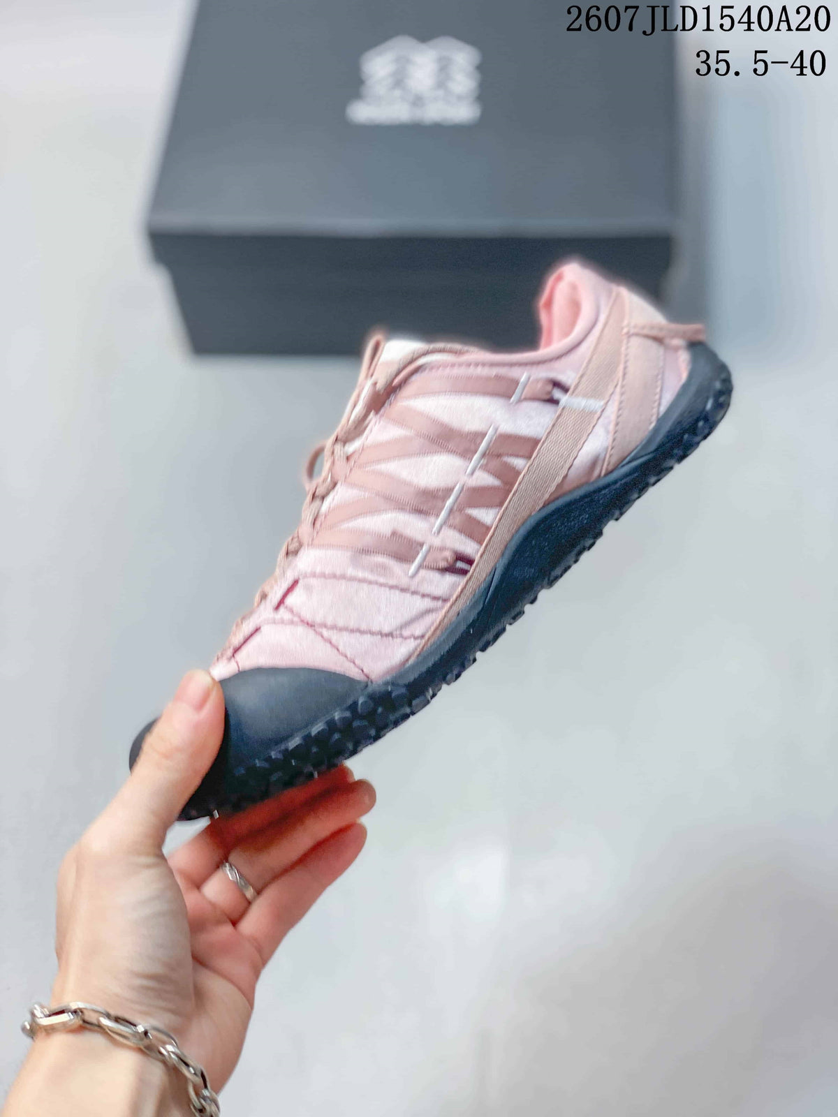 Side view of the pink sneaker showing layered panels, lace-up fastening, and black toe and outsole sections.