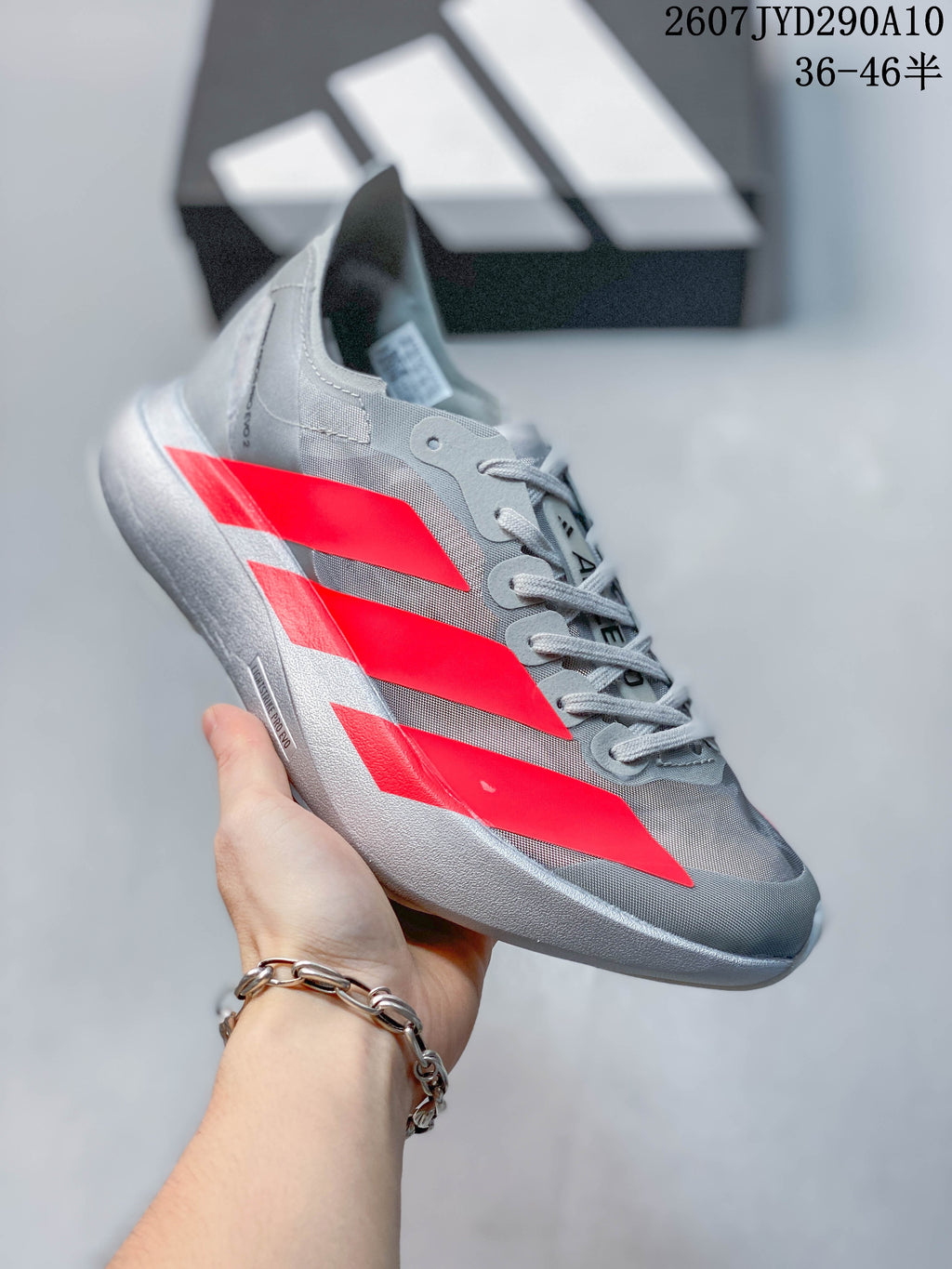 Angled side view showing the streamlined gray upper, red side detailing, laces, and thick light-colored sole.