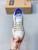 Top view of the sneaker showing the perforated white toe box, cream-colored laces, blue collar, and tongue label.