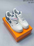 Pair of white and navy low-top sneakers with perforated toes and patterned laces, displayed on an orange box.