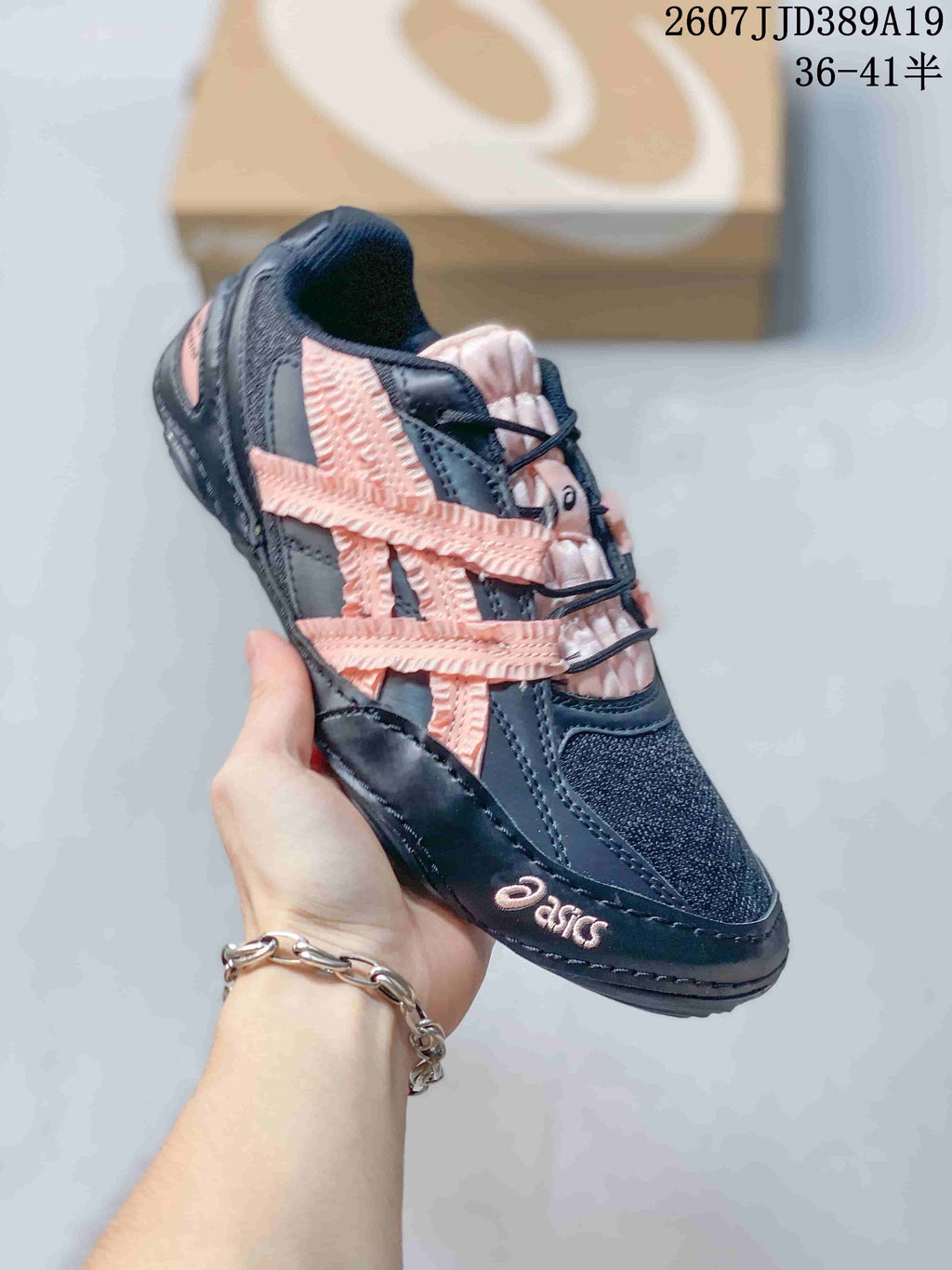 Angled side view of a black ASICS sneaker showing the pink side detailing, lace-up design, and ASICS branding.