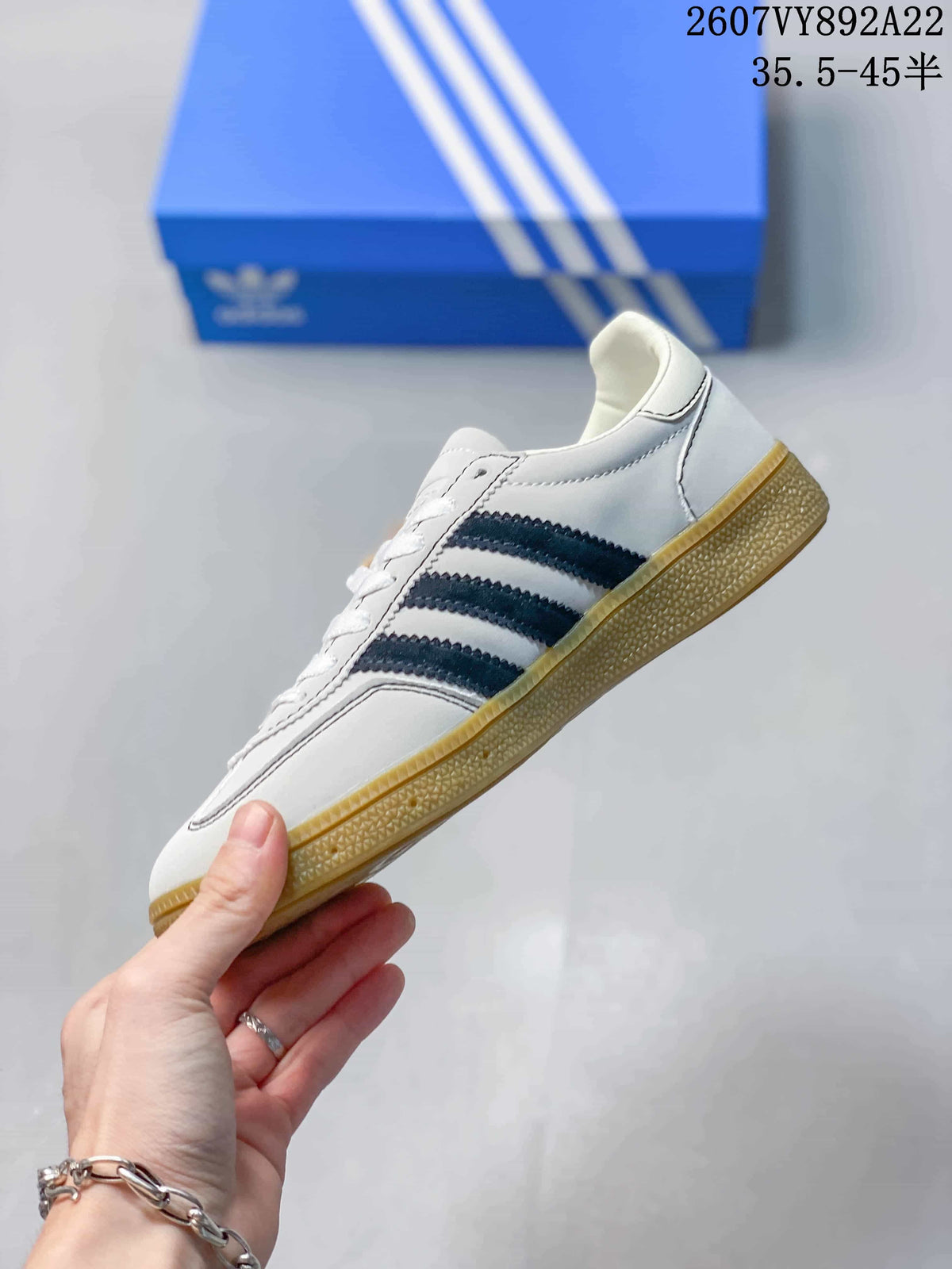 Side profile of the white sneaker with dark navy stripes, lace-up construction and gum sole.
