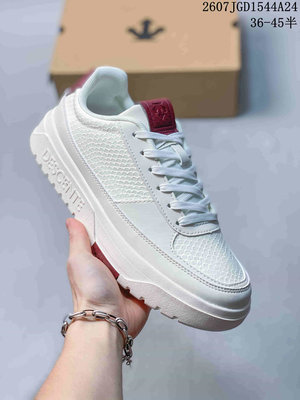 Angled side view of the white DESCENTE sneaker showing the textured upper, embossed midsole branding and outsole tread.