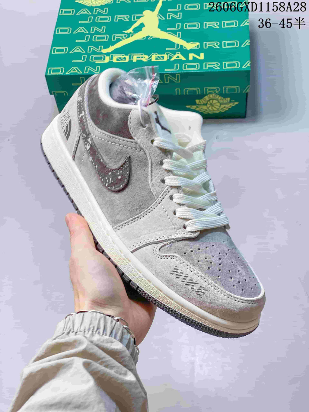 Angled view of the sneaker showing its grey panels, speckled Swoosh and detachable charm