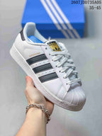 Angled close view showing the white upper, black stripes, Superstar text, and shell-style toe.