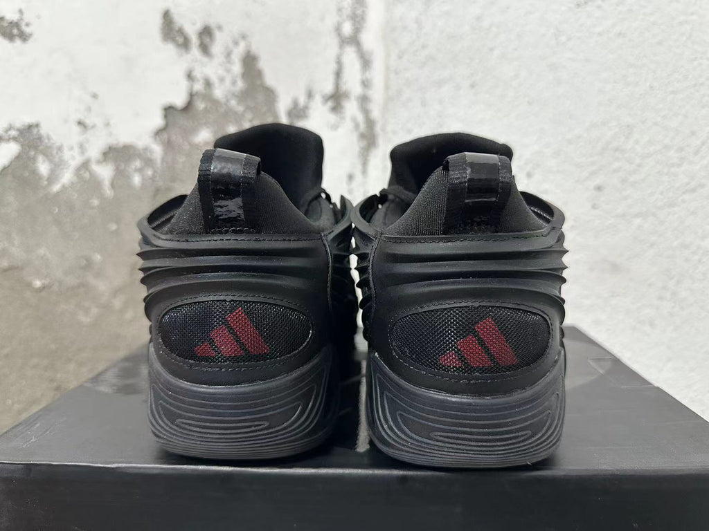 Rear view of black Adidas sneakers with red logo details and sculpted soles