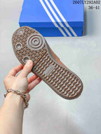 Brown sneaker outsole shown close up, featuring a textured geometric tread pattern and adidas branding.