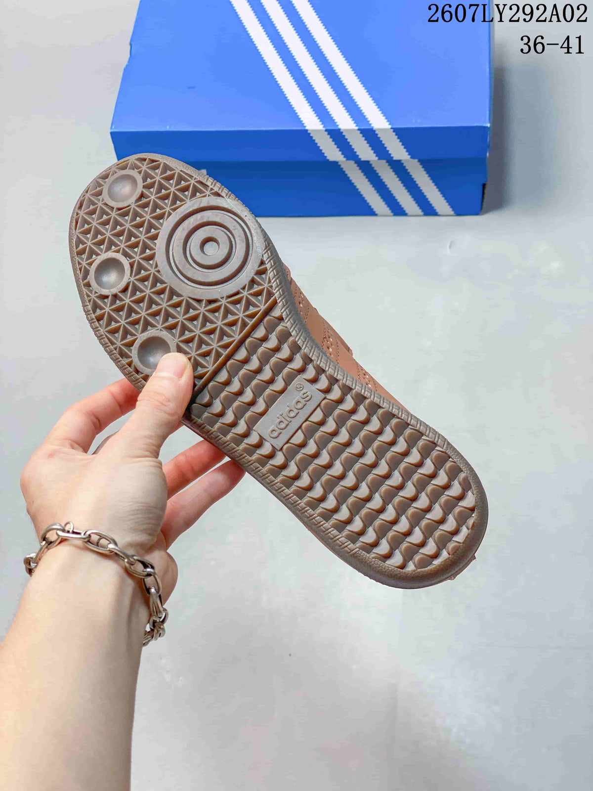 Brown sneaker outsole shown close up, featuring a textured geometric tread pattern and adidas branding.